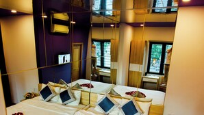 A large bed with white linens, multiple pillows, and heart-shaped flower arrangements. - Mata Love hotel (Da Nang)