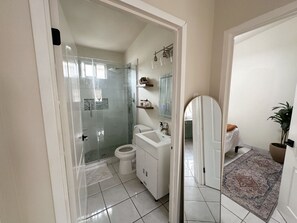 Een moderne badkamer met een douchecabine van glas, een witte wastafel en een grote spiegel.