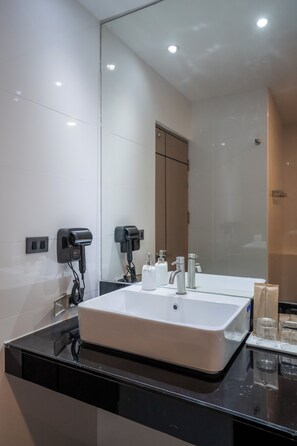 A modern bathroom with a large mirror, two hair dryers, a sink, and a shower area. - Sunnyside Kata (Karon)