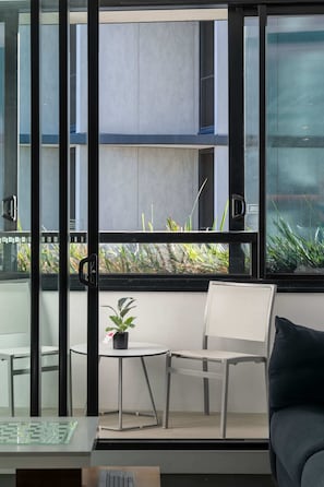 Une chambre moderne avec une porte vitrée donnant sur un espace extérieur, une petite table avec une chaise et une plante en pot.