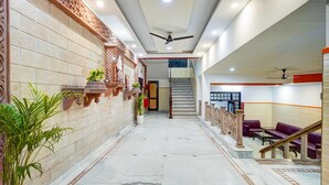 Un'hall d'hotel con pavimento in marmo, una scala e un'area salotto con divani.