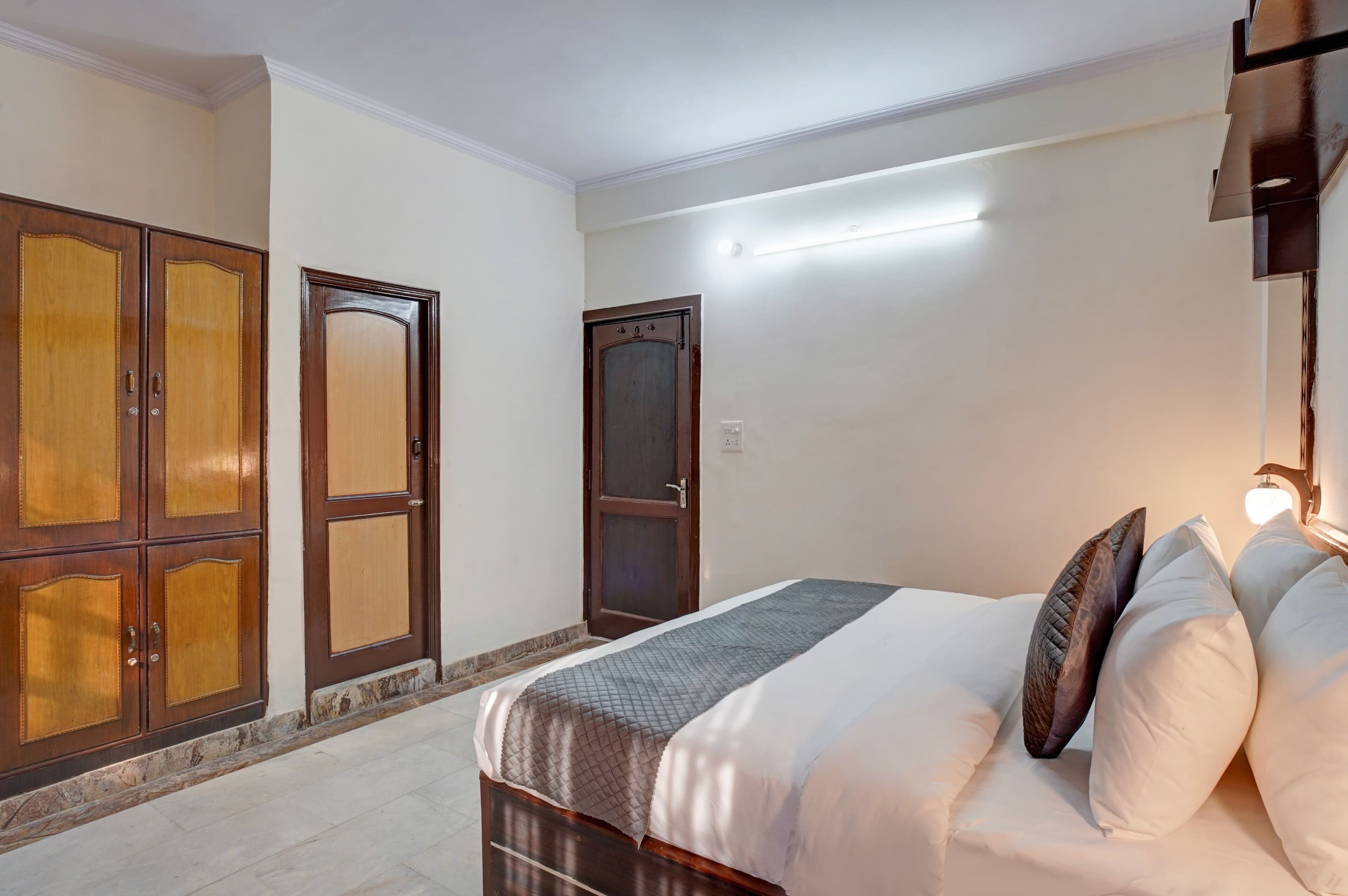 A bedroom with a bed, wooden wardrobe, and a door.
