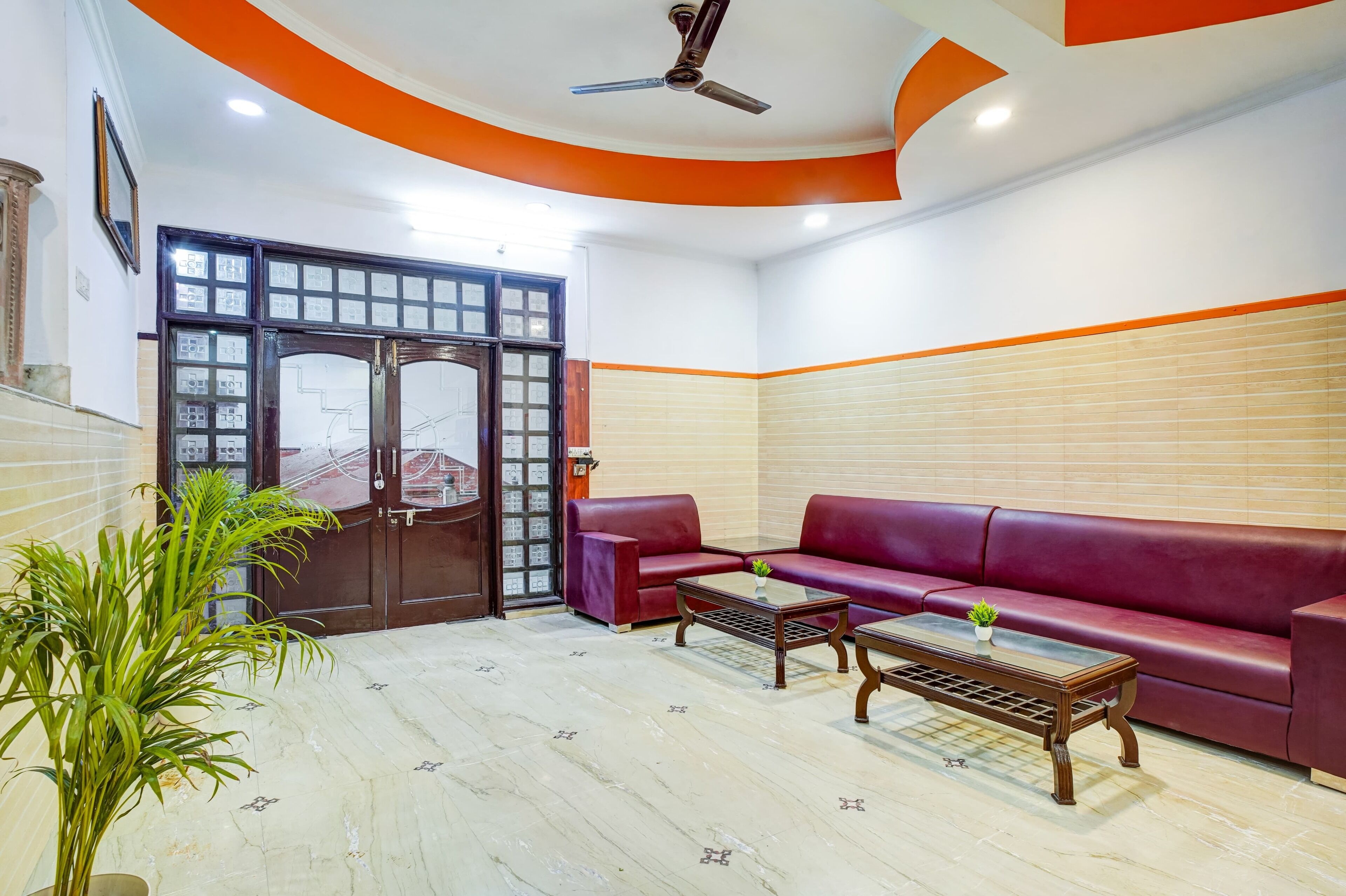 A living room with a red sofa, two coffee tables, and a ceiling fan.