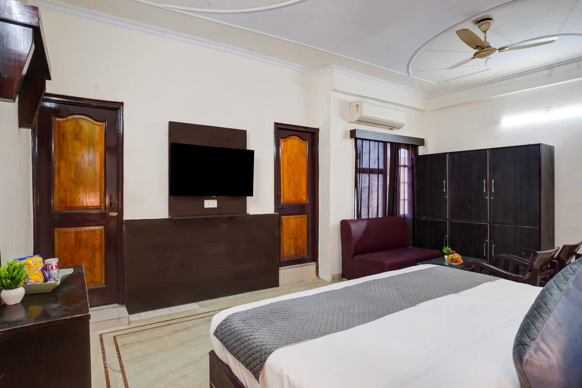Una habitación de hotel con una cama, un televisor montado en la pared, un armario y un ventilador de techo.