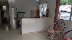 A kitchen with a refrigerator, a sink, and a window with curtains.