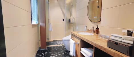 A modern bathroom with a glass shower enclosure, a marble-tiled floor, a sink with a vanity, and a mirror.