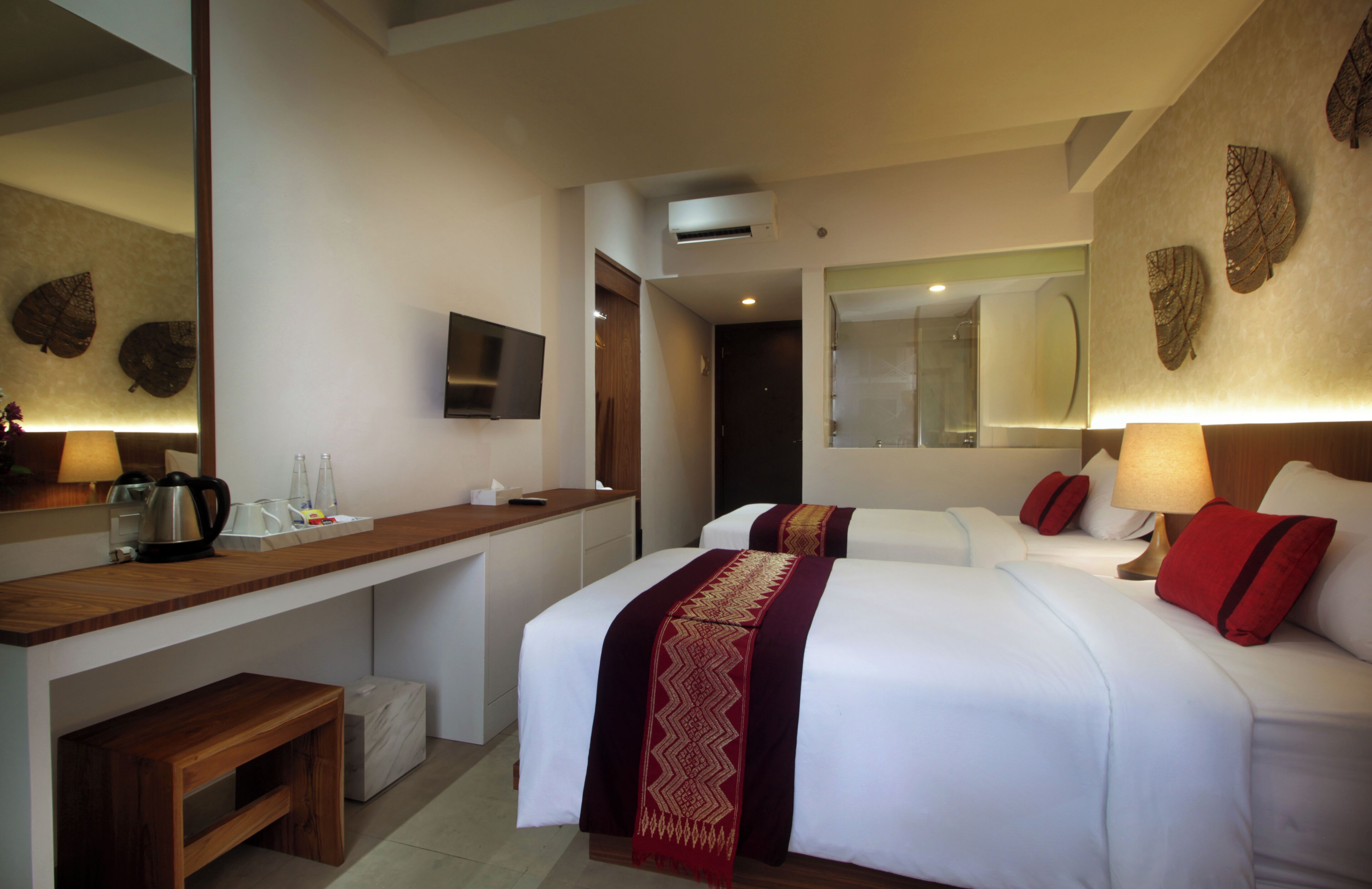 A hotel room with two beds, a wooden desk, a TV, and a mirror.