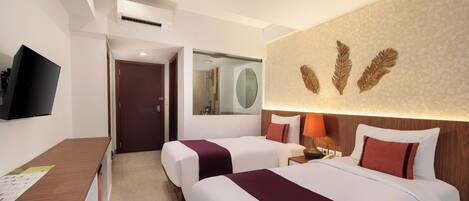 A hotel room with two beds, a desk, a television, and a mirror.