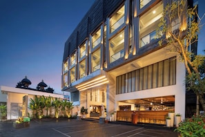 A modern hotel with a spacious courtyard, large windows, and a well-lit entrance.