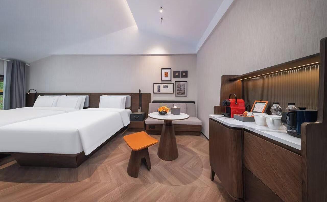 Ein Hotelzimmer mit einem Doppelbett, einem kleinen runden Tisch mit einer Vase, einer Kaffeemaschine und einer Mikrowelle auf der Ablagefläche.