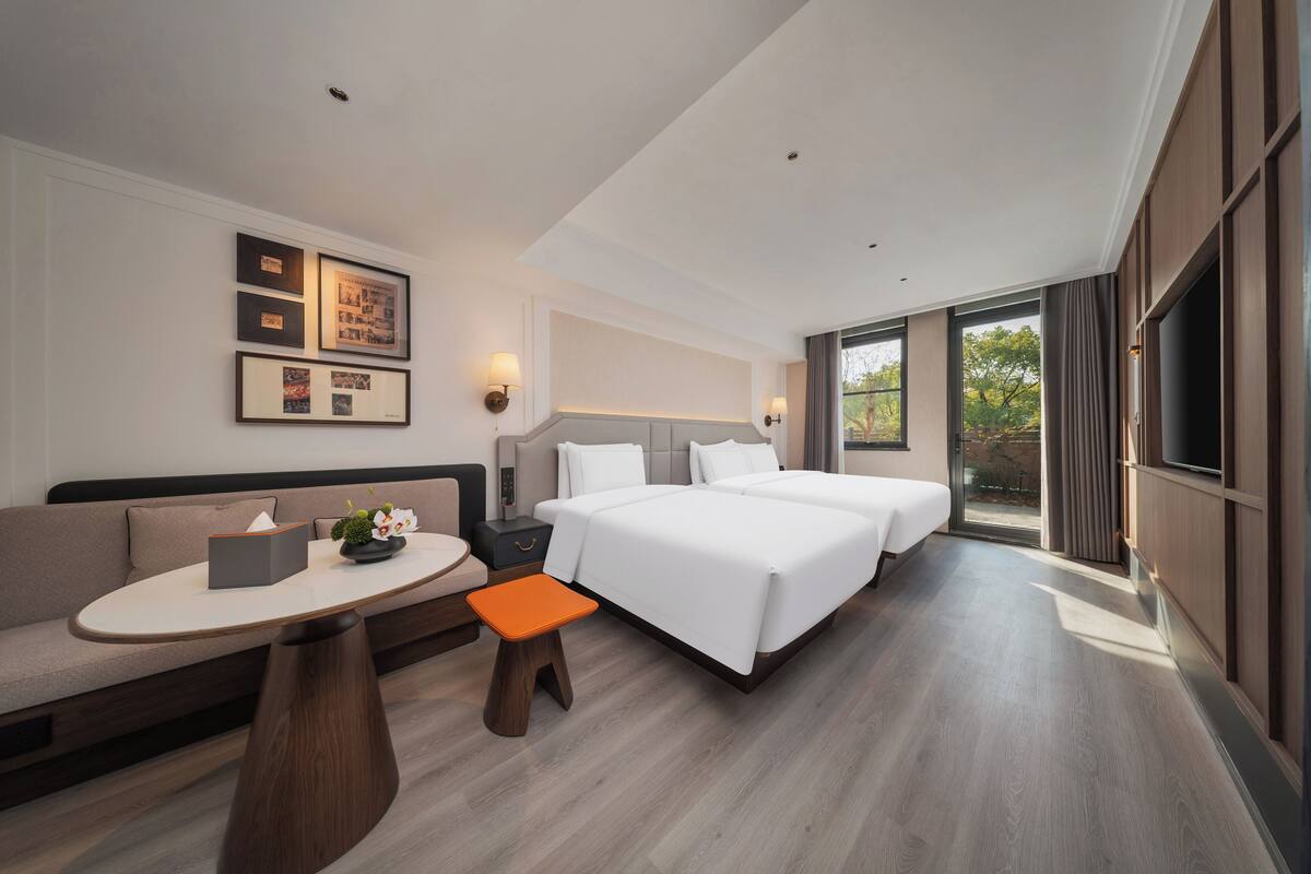 Una habitación de hotel moderna con sofá, una mesita, una mesita de noche, una cama y televisor.