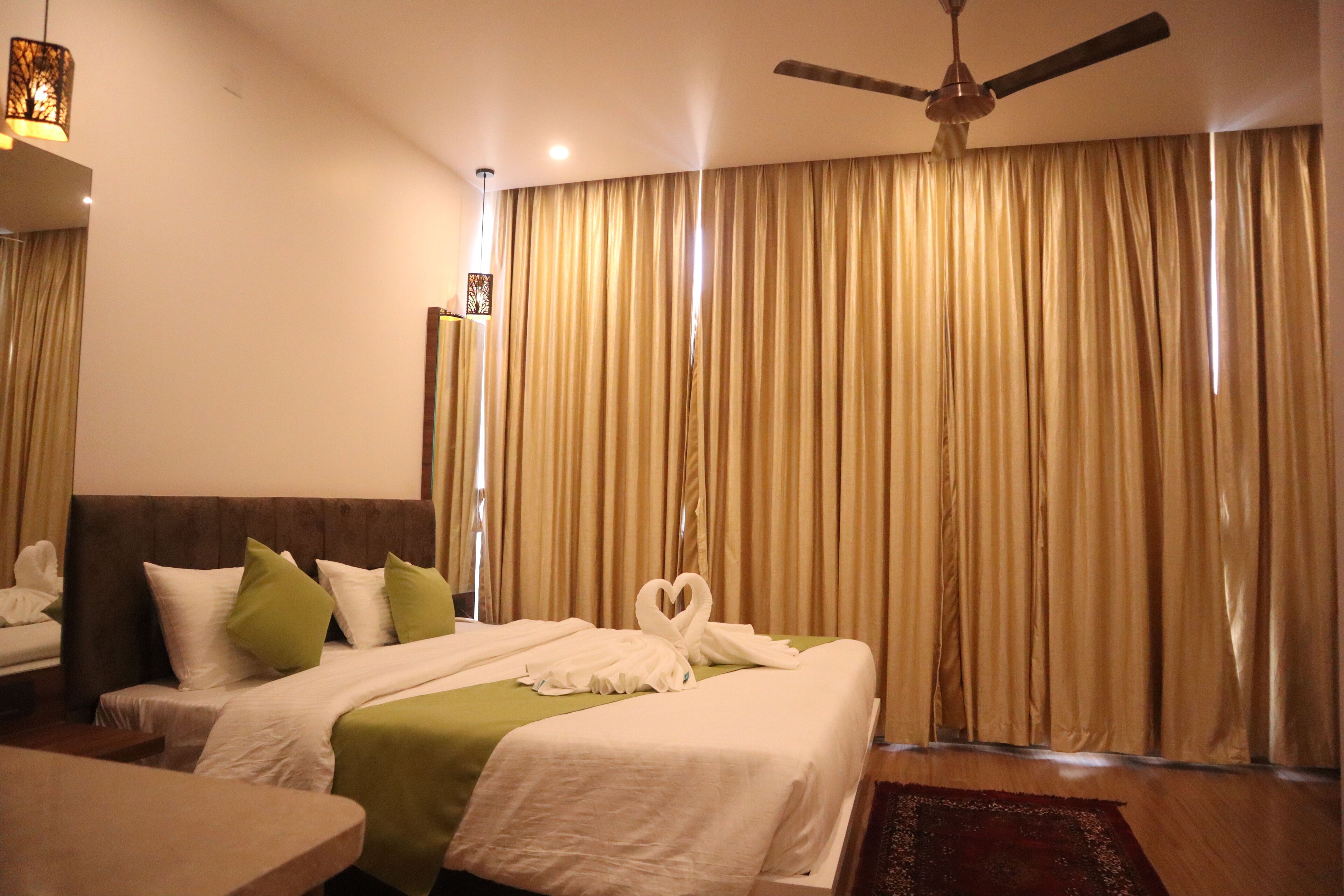 A hotel room with a bed, a ceiling fan, and curtains.