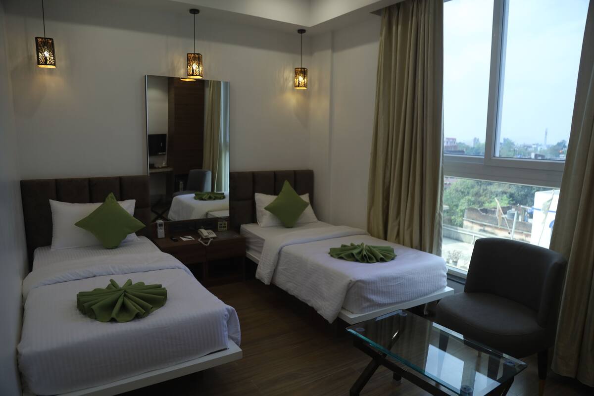 A hotel room with two beds, a glass table, a chair, a nightstand, and a large window with a view.