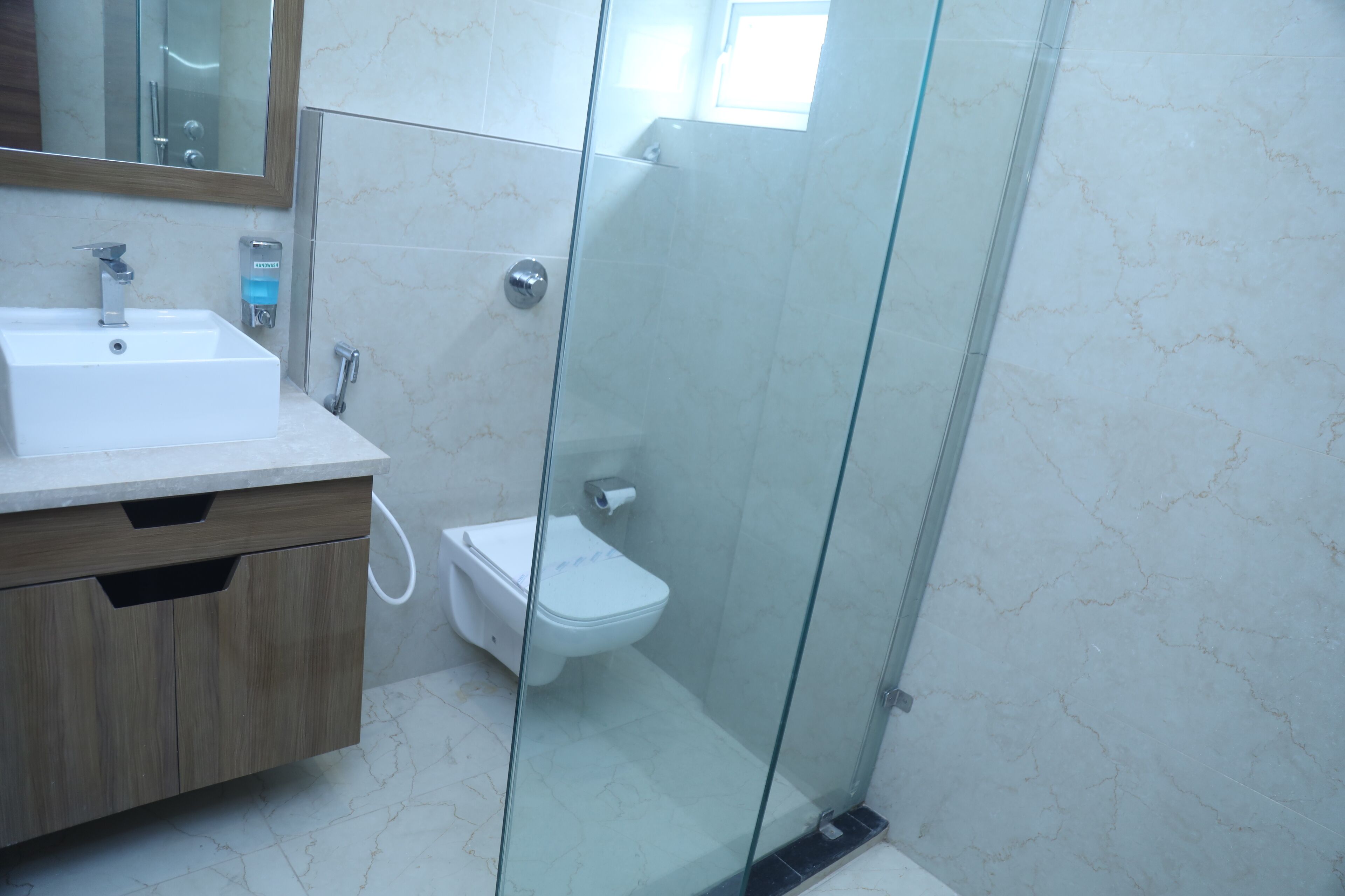 A bathroom with a glass-enclosed shower, a white sink, and a toilet.