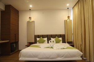 Una habitación de hotel con una cama grande, un armario de madera, una mesita de noche y un espejo.