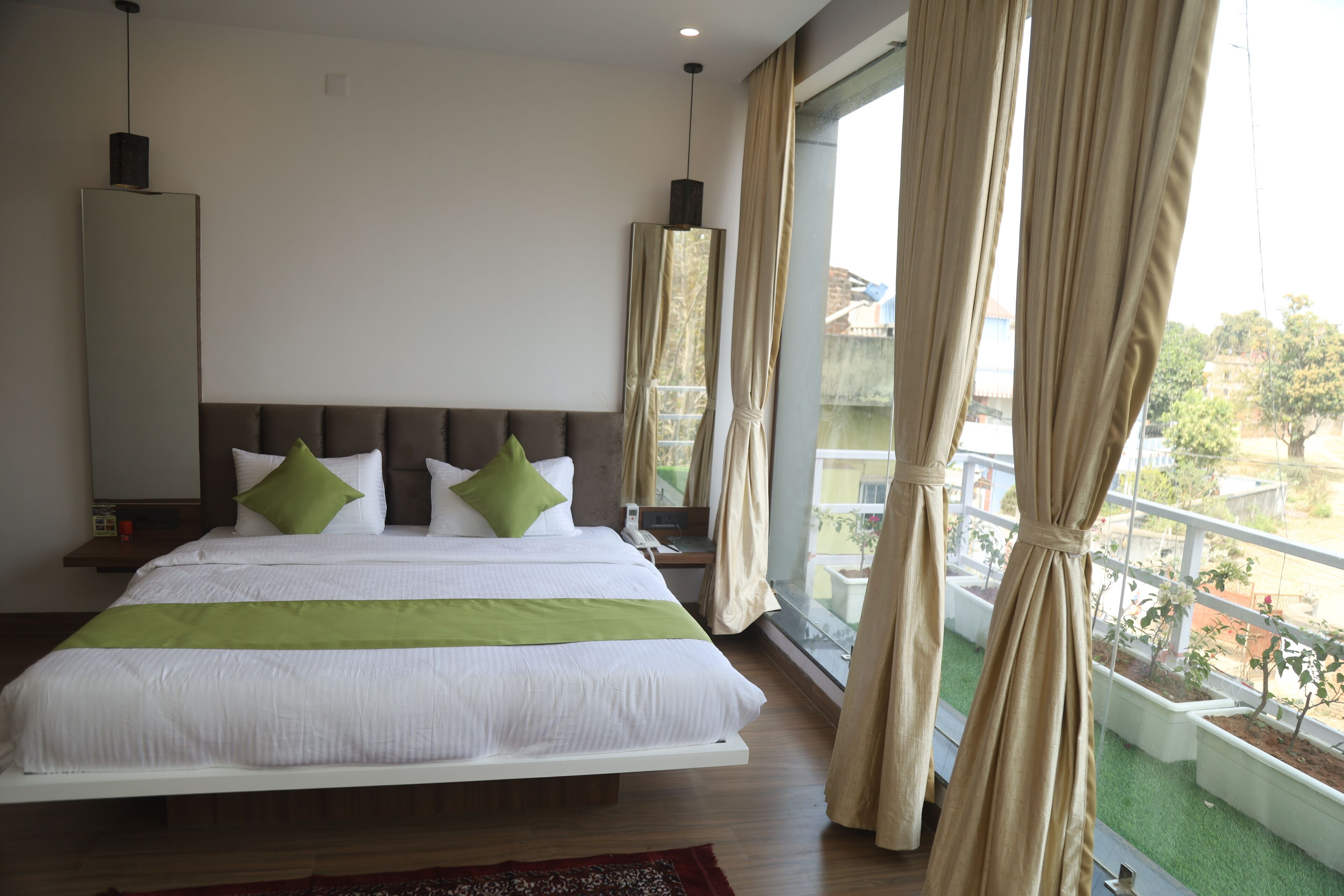 A modern hotel room with a large bed, a nightstand, a mirror, and a view of the outside balcony.