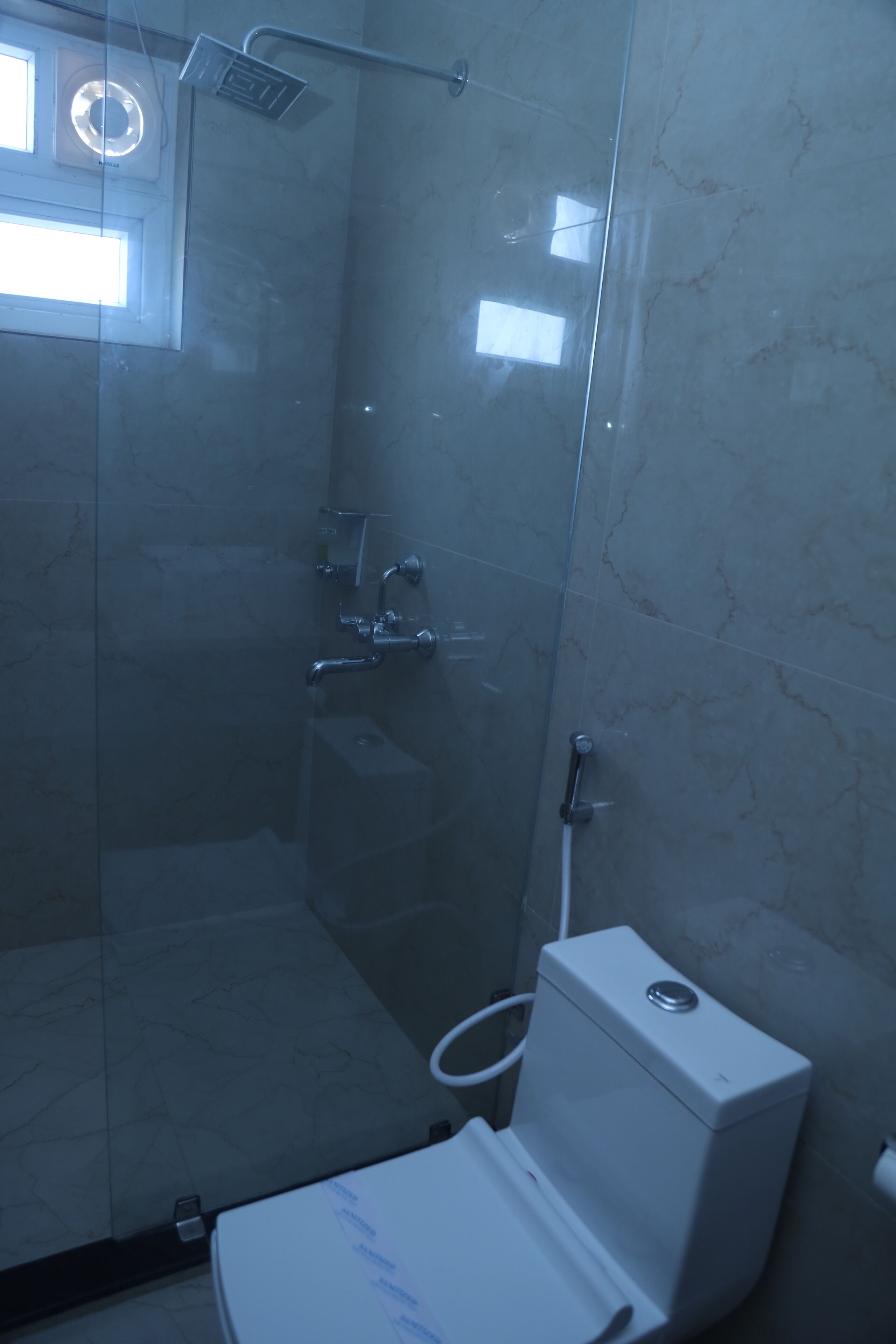 A glass-enclosed shower stall with a toilet and sink.