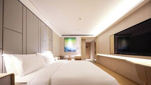 A modern hotel room with a large bed, a flat-screen TV, and a desk with a chair. - Full Season Hotel (Qingdao)