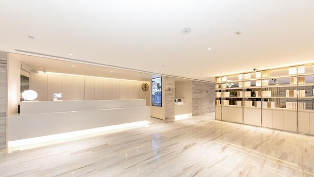 A modern hotel lobby with a reception desk, digital display, and a well-lit interior. - Full Season Hotel (Qingdao)