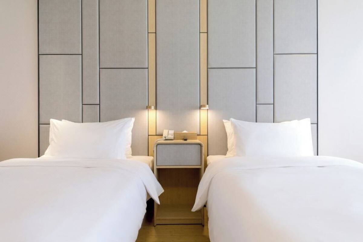 A hotel room with two beds, a nightstand, and a wall with a geometric pattern.