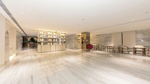 A spacious lobby with a marble floor, a reception desk, and seating area. - Full Season Hotel (Qingdao)
