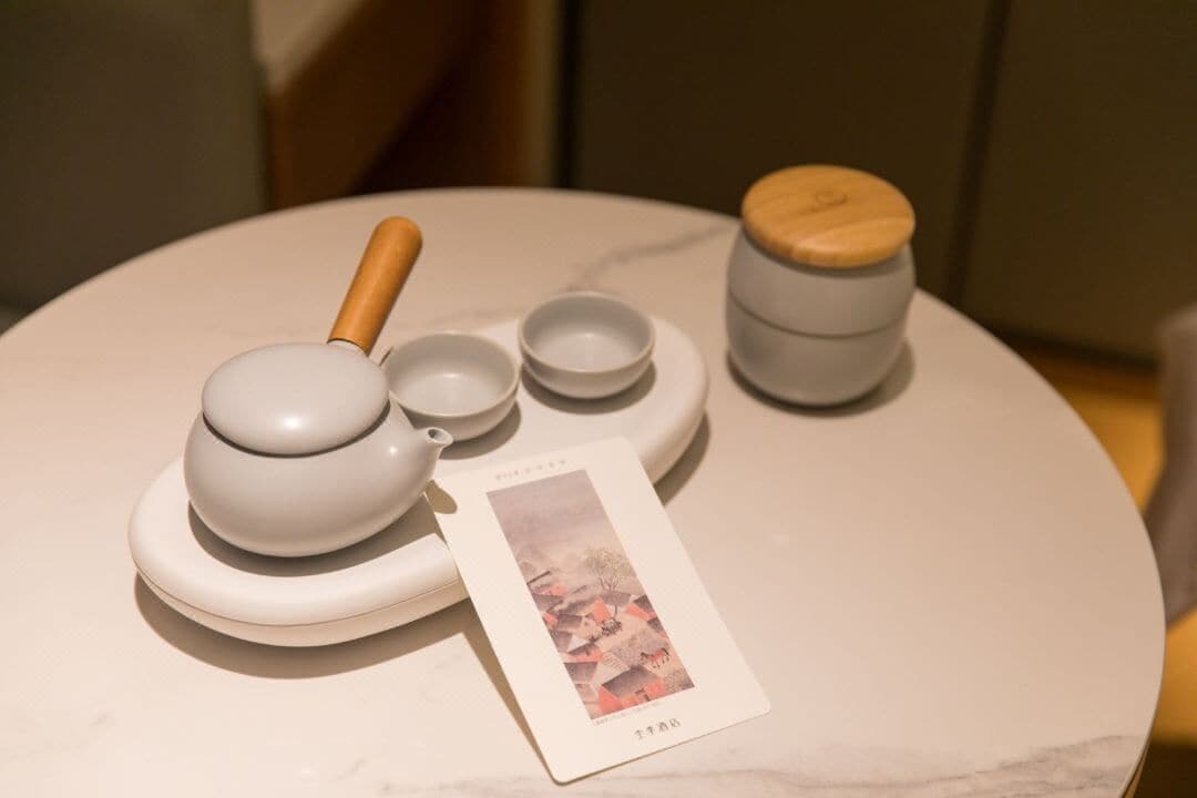 Un juego de té con un asa de madera, una tetera y dos tazas sobre una mesa de mármol.