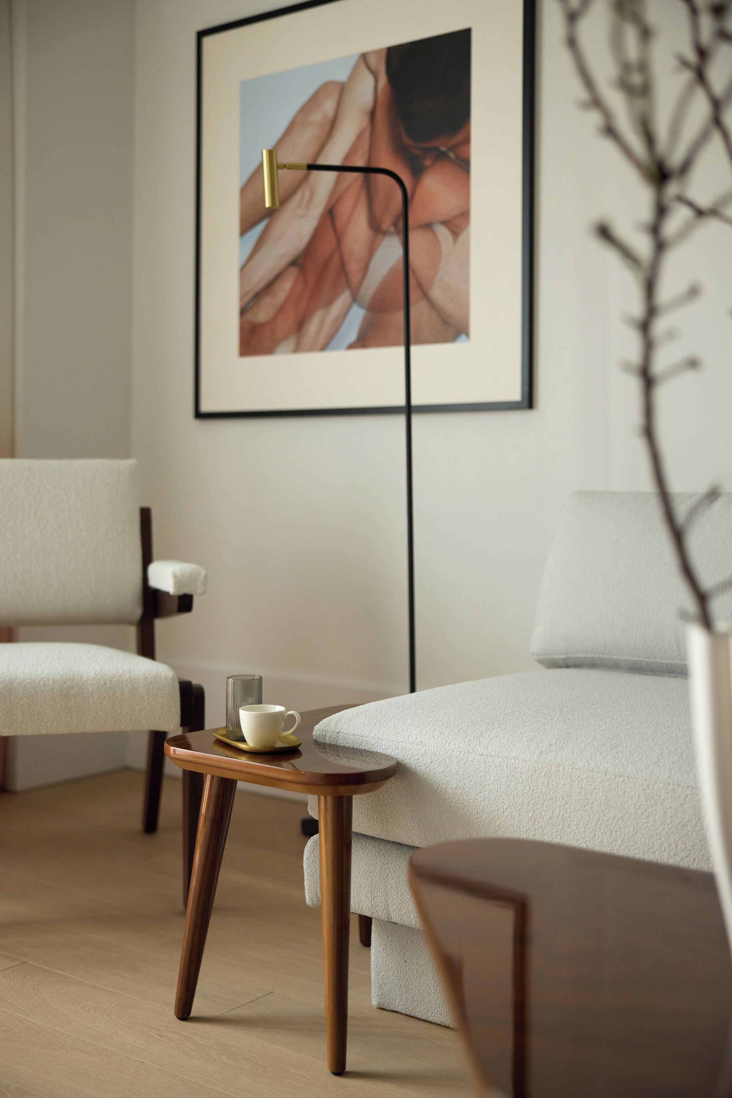 A modern, minimalist room with a sofa, a small wooden table with a cup and saucer, and a framed picture on the wall.