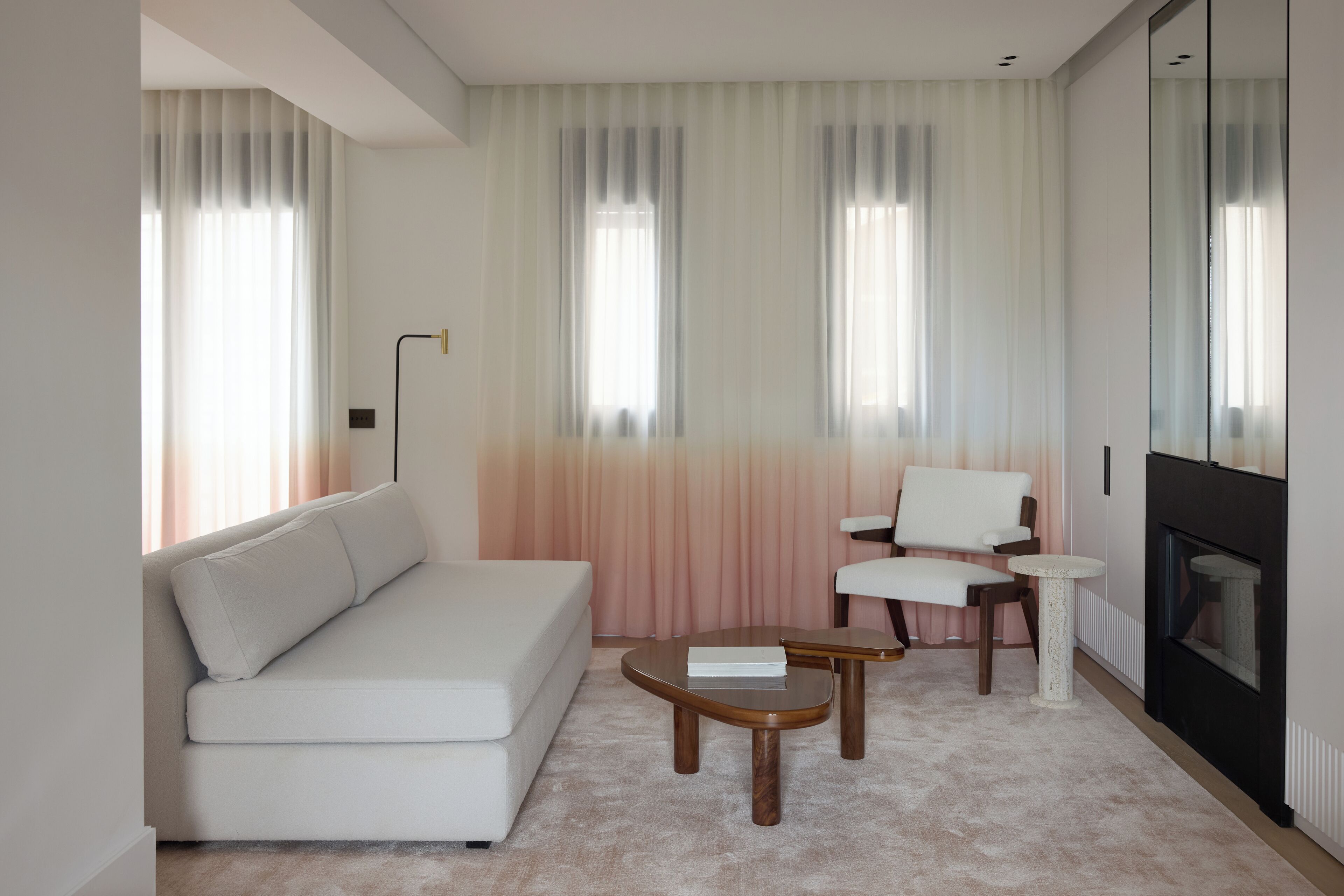 A modern living room with a white sofa, a small round table, a chair, and a fireplace.