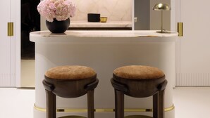 Une cuisine moderne avec un plan de travail blanc, deux tabourets et un vase de fleurs.