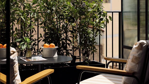 Un balcon avec une table, des chaises et des plantes en pot.