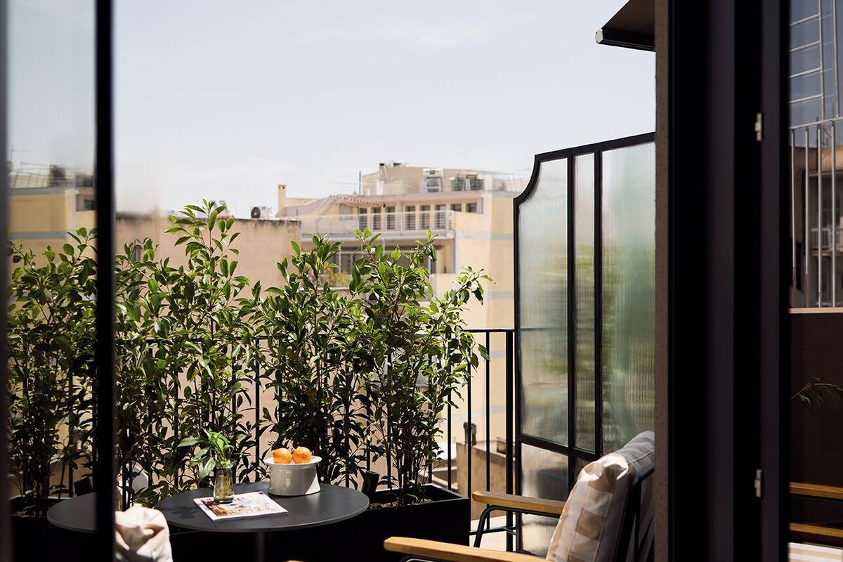 A balcony with two chairs, a table, and potted plants.