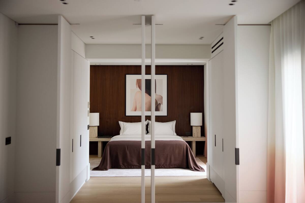 A modern hotel room with a large bed, bedside tables, and a wooden accent wall.