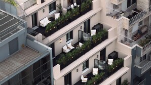 Un immeuble résidentiel à plusieurs étages, doté de balcons, dont certains sont ornés de plantes et aménagés avec des espaces pour s’asseoir à l’extérieur.