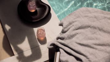 A towel and a glass of water by a poolside.