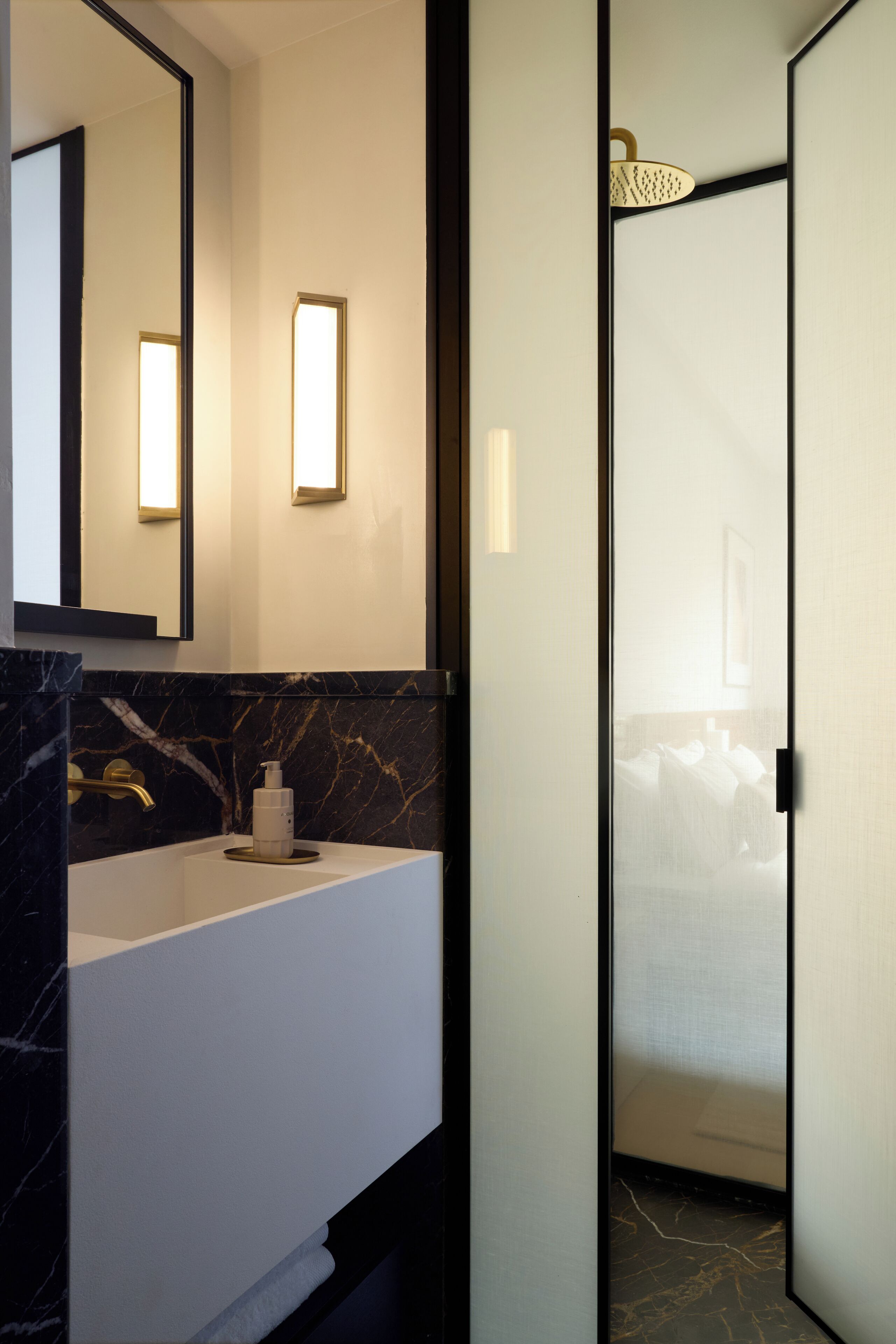 A modern bathroom with a white sink, marble backsplash, and a large mirror.