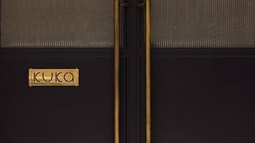 A black door with two brass handles and a nameplate reading "KUKA".