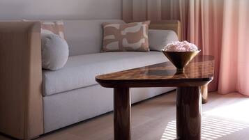 A modern living room with a sofa, a coffee table, and a large window with curtains.