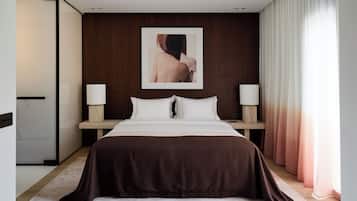 A modern hotel room with a large bed, two bedside tables, a framed picture on the wall, and a window with curtains.