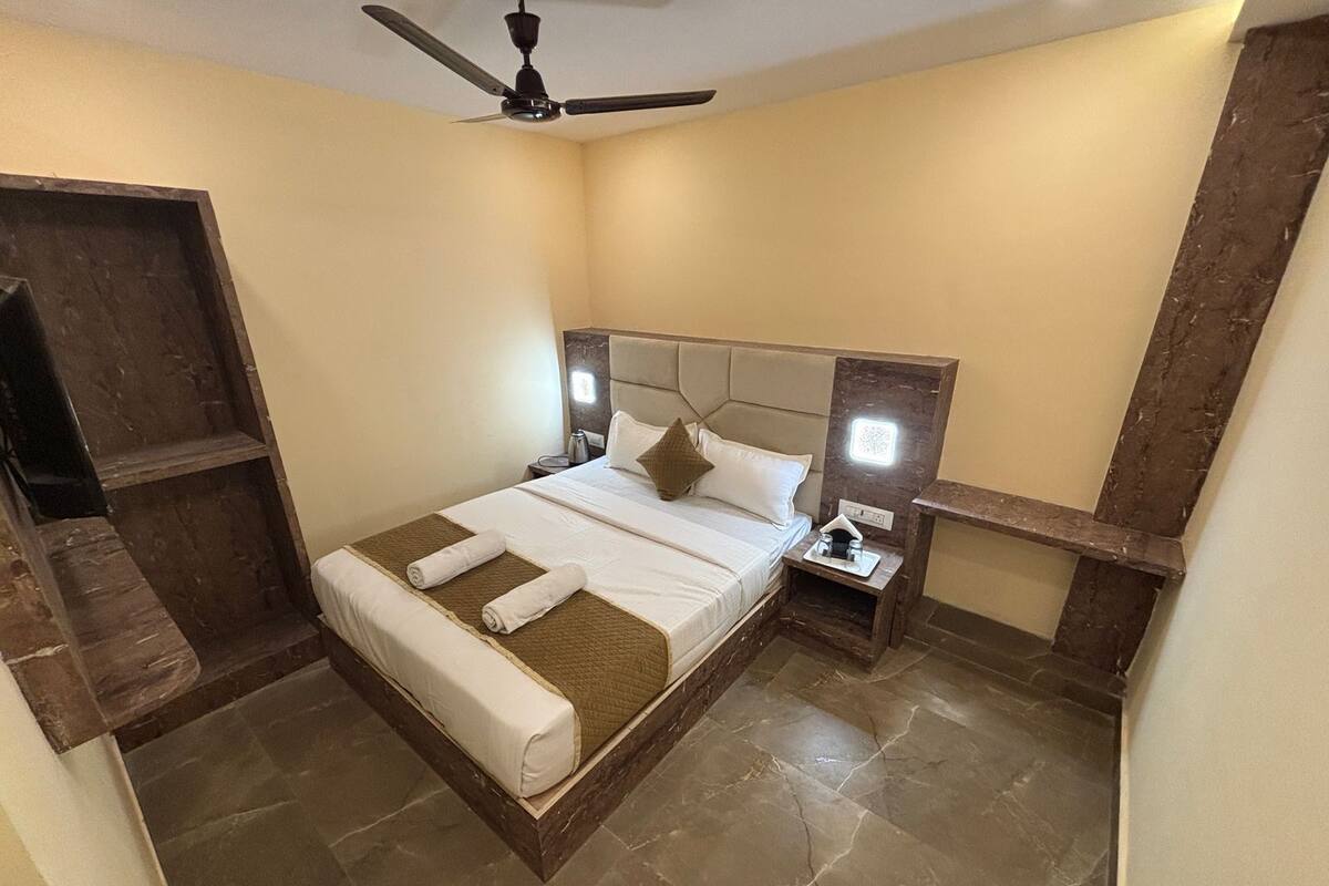 A bedroom with a bed, nightstands, a ceiling fan, and a wooden bench.