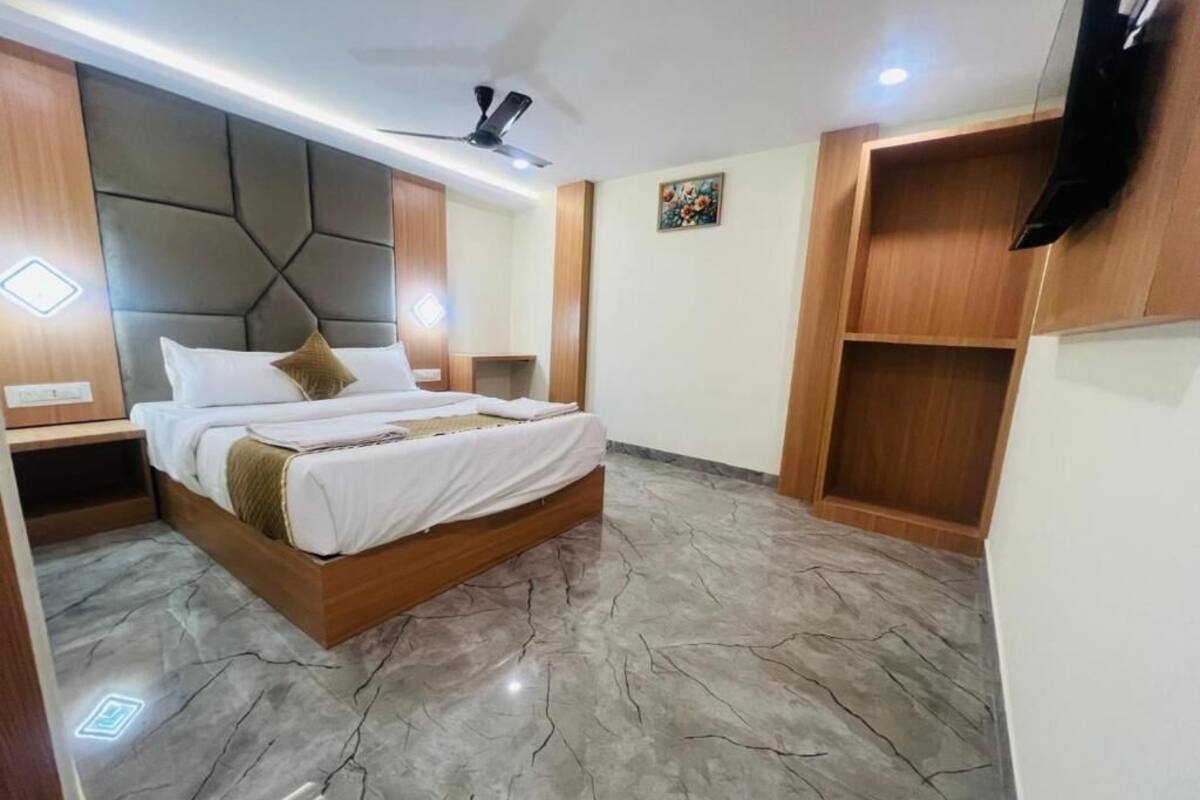 A modern bedroom with a large bed, wooden headboard, and built-in shelving.