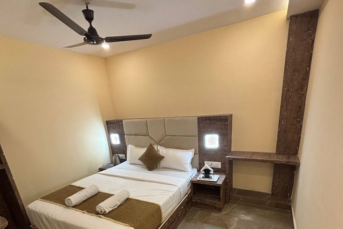 A bedroom with a bed, a nightstand, a ceiling fan, and a marble floor.