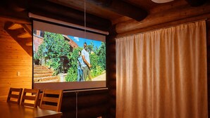A room with a wooden interior, a projection screen, a table, and a curtain. - Hirafu Cottage (Kutchan)