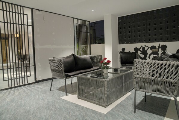 A modern living room with a glass coffee table, two wicker sofas, and a decorative wall panel.