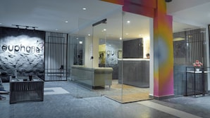 A modern reception area with a glass partition, a sofa, and a reception desk. - Hotel Euphoria Urban Sleep (Hyderabad)