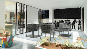 A modern interior with wicker furniture, a glass partition, and a wall with silhouettes. - Hotel Euphoria Urban Sleep (Hyderabad)