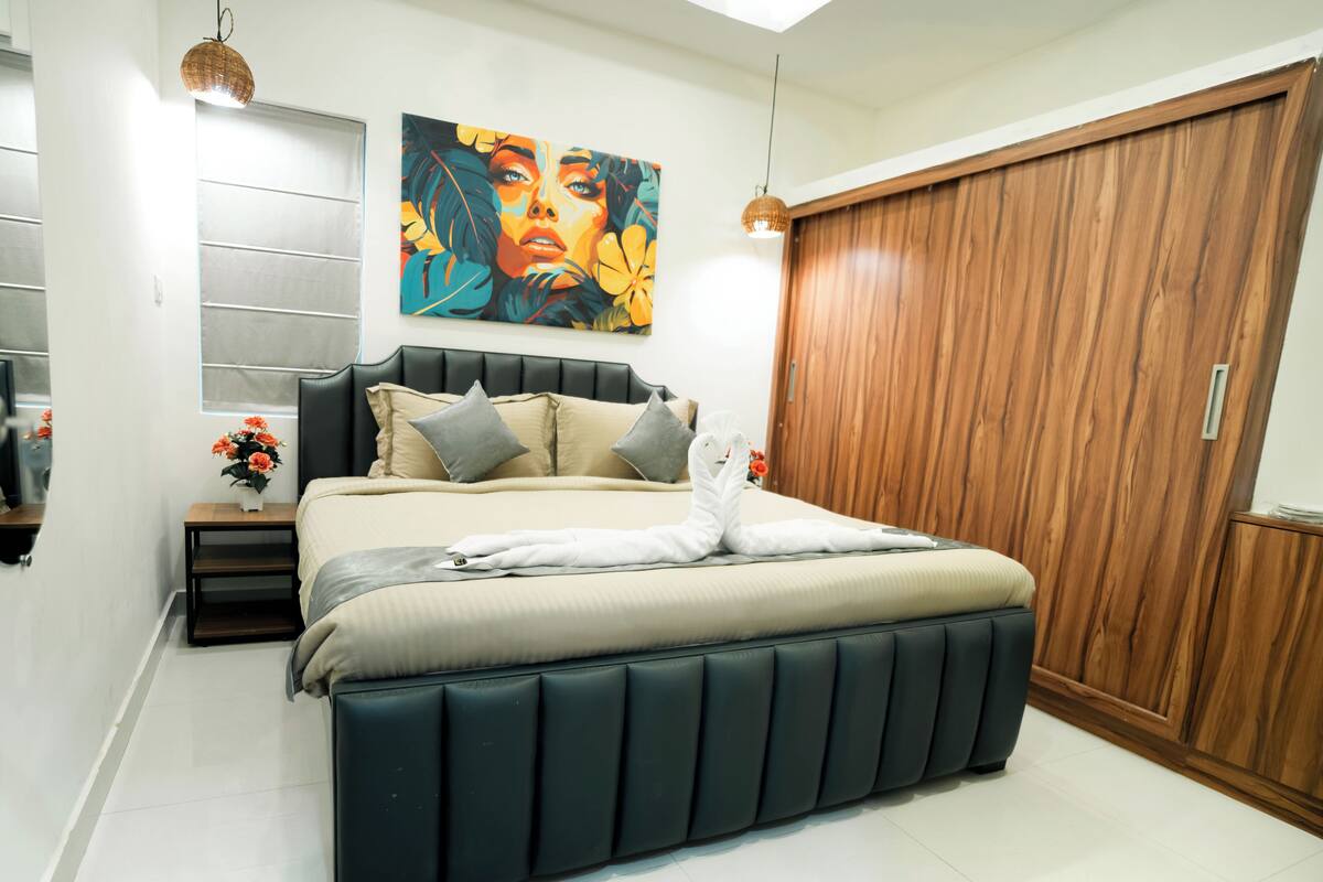 Een moderne slaapkamer met een groot bed, een houten garderobe en een schilderij aan de muur.