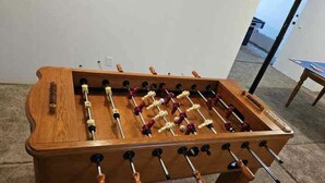 Una mesa de fútbol de madera con varias barras y figuras, sobre un piso alfombrado.