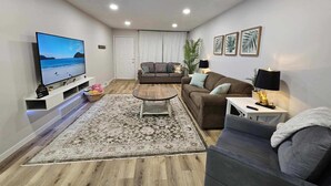 Un salon moderne avec un téléviseur à écran plat, un canapé, une table basse et un tapis.
