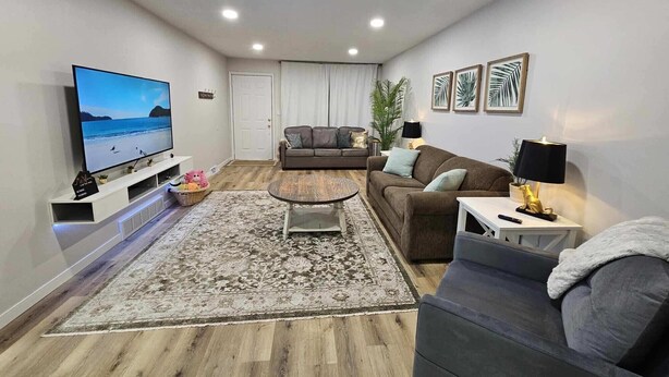 Una sala de estar moderna con un televisor de pantalla plana, un sofá, una mesa de centro y una alfombra.