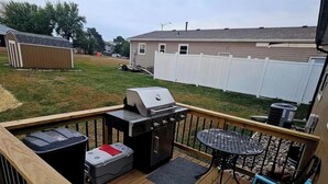 A deck with a grill, outdoor seating, and a view of a residential area. - Swiss Chalet (Sioux Falls)